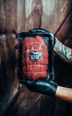 a person holding up a piece of raw meat in their left hand and wearing black gloves