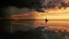 a sailboat floating in the middle of a body of water under a cloudy sky