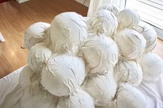 a large pile of white balls sitting on top of a wooden floor next to a window