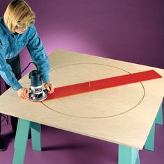 a woman sanding down a piece of wood with a power tool on top of it