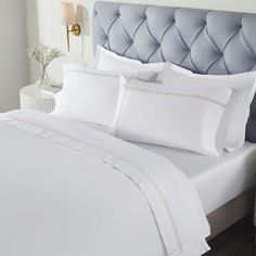 a bed with white sheets and pillows in a room