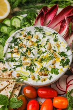 a bowl of dip surrounded by vegetables and crackers