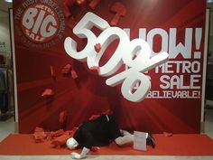 a man laying on the ground in front of a big sale sign