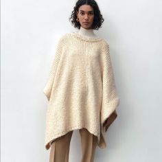 Ecru Cozy Sweater Poncho Oversized Chic Wool Poncho, Oversized Cape Sweater For Fall, Cozy Winter Cape With Batwing Sleeves, Beige Knit Poncho For Spring, Oversized Knitted Winter Cape, Spring Beige Knit Poncho, White Knit Poncho For Fall, Oversized Beige Wool Sweater, Beige Knit Poncho One Size