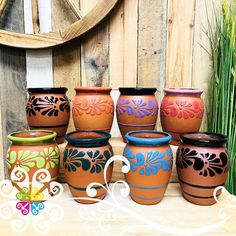 a group of vases sitting on top of a wooden table next to tall grass