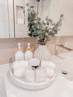 a white bathroom sink with soap and lotion on the counter next to a mirror