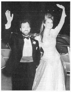 a black and white photo of a bride and groom waving at the camera with their arms in the air