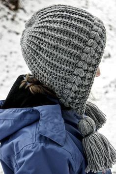 a person wearing a hat and scarf in the snow with their back to the camera