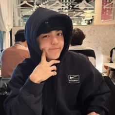 a person sitting at a table with a plate of food in front of them and wearing a black hoodie