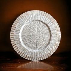 a clear glass plate sitting on top of a wooden table next to a brown wall