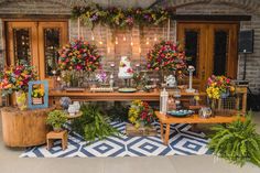 a table topped with lots of different types of flowers and plants next to a brick wall