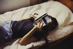 a woman laying in bed reading a book