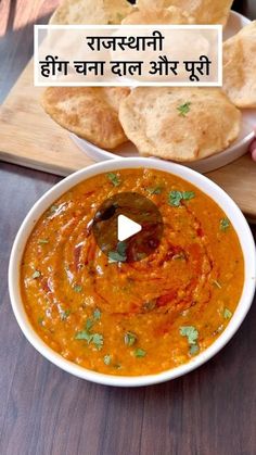 a bowl of soup and some bread on a cutting board with an advertisement in the background