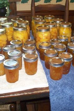 jars filled with pickles sitting on top of a blue table cloth next to a potted plant