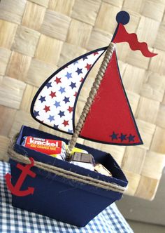 a toy sailboat on top of a blue box filled with candy and other items