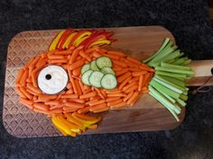 a fish made out of carrots and cucumbers on a cutting board