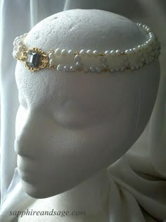 The "Amalie" Circlet Headpiece is a luxurious statementpiece, sure to elevate any ensemble. Showcasing a single-colored center stone, surrounded by a crown of white pearls, this headpiece is perfect for your special day. Be breathtakingly beautiful! Approximately 20-21" in length. Can be worn around the head, or tipped forward from the crown of the head down toward the forehead. Elegant Ceremonial Crown Headpieces, Elegant Silver Beaded Headpiece, Adjustable Crown Design Headpiece For Weddings, White Crown Design Jewelry For Wedding, Elegant Headpiece With Tall Crown Design, Elegant Tall Gold Crown, Elegant Silver Headpiece With Structured Crown, Elegant Adjustable Crown For Wedding, Elegant Evening Headpieces With Bead Caps