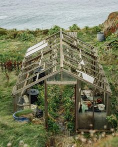 a small wooden structure sitting on top of a lush green hillside next to the ocean