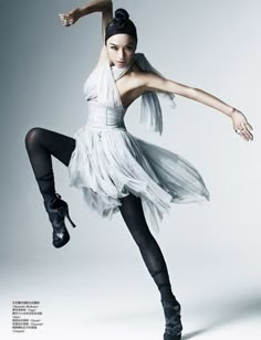 a woman in a white dress and black tights is dancing with her arms stretched out