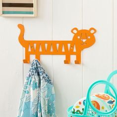 an orange metal animal coat rack on a white wall next to a blue and green basket