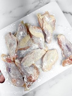 raw chicken wings on a cutting board with powdered sugar