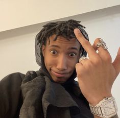 a young man with dreadlocks making the peace sign while holding his hand up in front of him