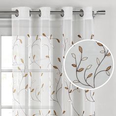 a white curtain with gold leaves on it and a circle window valance in the background