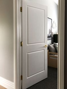 an open door leading to a bedroom with white walls and carpeting on the floor