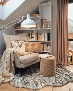 a chair and ottoman in front of a bookshelf with a lamp above it