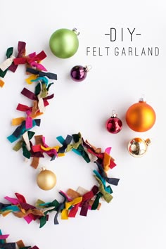 an assortment of christmas ornaments on a white surface with colorful streamers and baubles