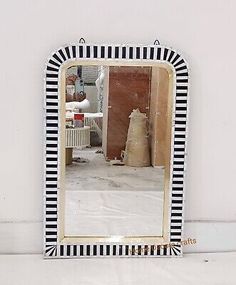 a black and white striped mirror sitting on top of a table next to a wall