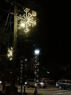 a snowflake is lit up in the night sky above a parking lot at an intersection