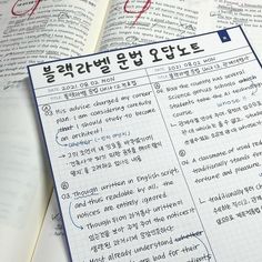 an open book with korean writing on it next to a pen and paper clipping