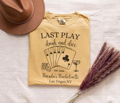 a t - shirt that says last play, drink and dice next to a straw hat