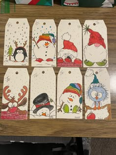 christmas tags with snowmen and penguins on them are sitting on a table next to other items