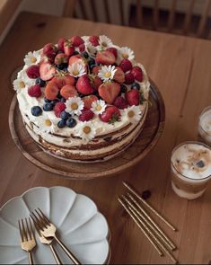 there is a cake with strawberries and blueberries on it next to two forks