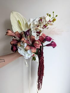 a bouquet of flowers is being held up against a wall by someone's arm