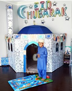 a young boy standing in front of a blue and white house shaped like a tent