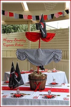 a table set up for a birthday party with an umbrella and pirate hats on it