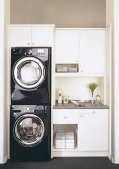 a washer and dryer in a small room with white cabinets on the wall