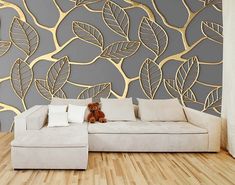 a white couch sitting on top of a wooden floor next to a wall covered in leaves