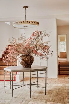 a vase with flowers sitting on top of a table in a living room next to stairs