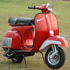 a red scooter is parked in the grass