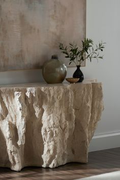 two vases sitting on top of a table next to a painting and potted plant