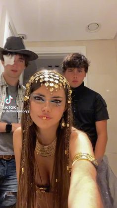 two men and a woman are taking a selfie in front of the camera, wearing headdress