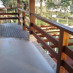 a balcony with wooden railings and tiled flooring next to a tree lined yard