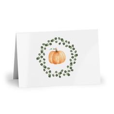 a white card with an orange pumpkin and green leaves in the center, on a white background