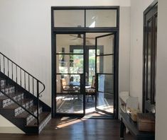 an open door leading to a living room with wooden floors and black railings on the second floor