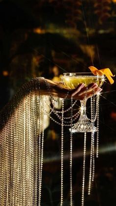 a person holding a glass with chains hanging from it