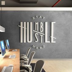 an office with multiple computers and chairs in front of a wall that says stay humble hard